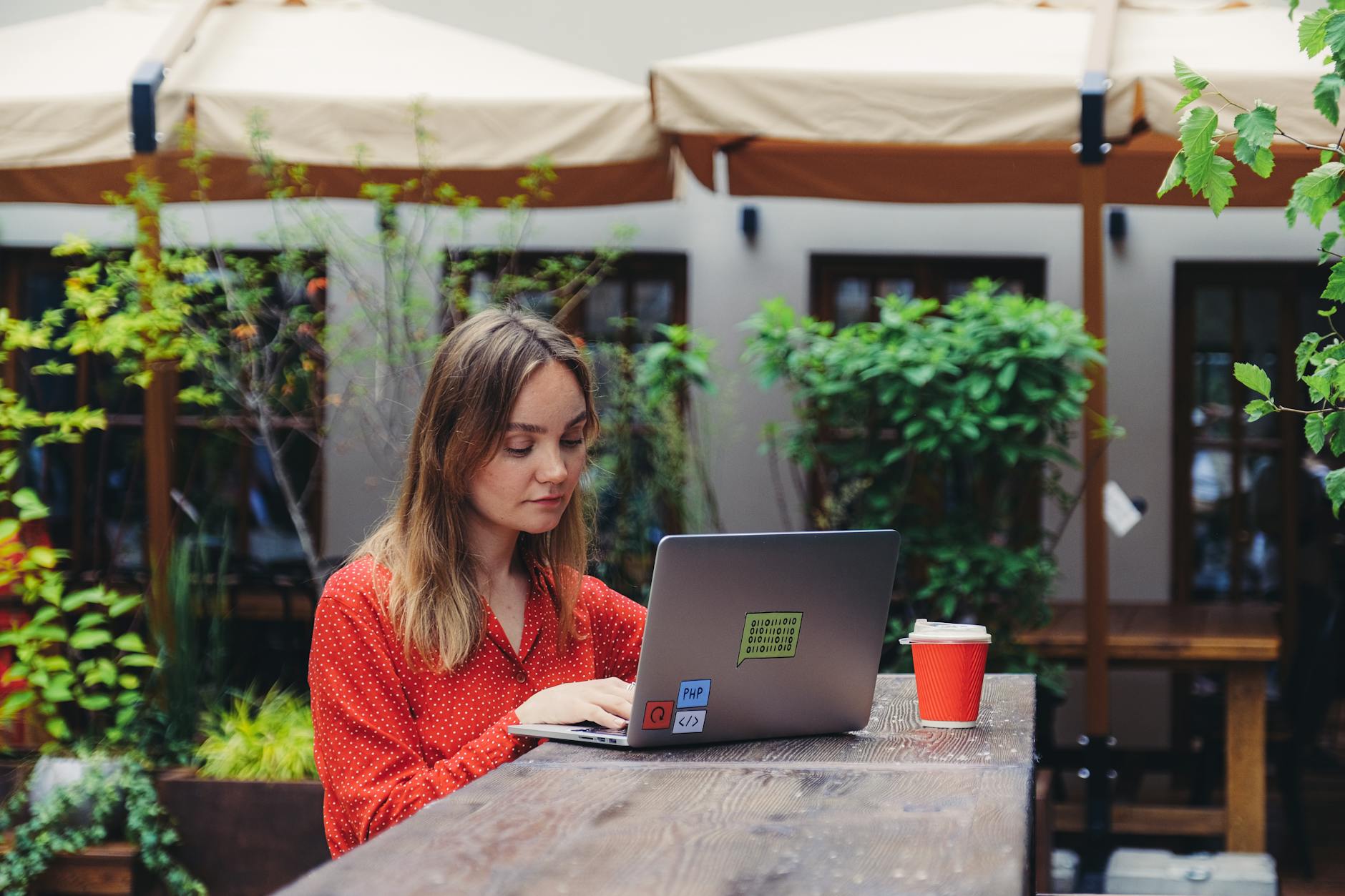 Young woman working on a laptop in an outdoor cafe setting