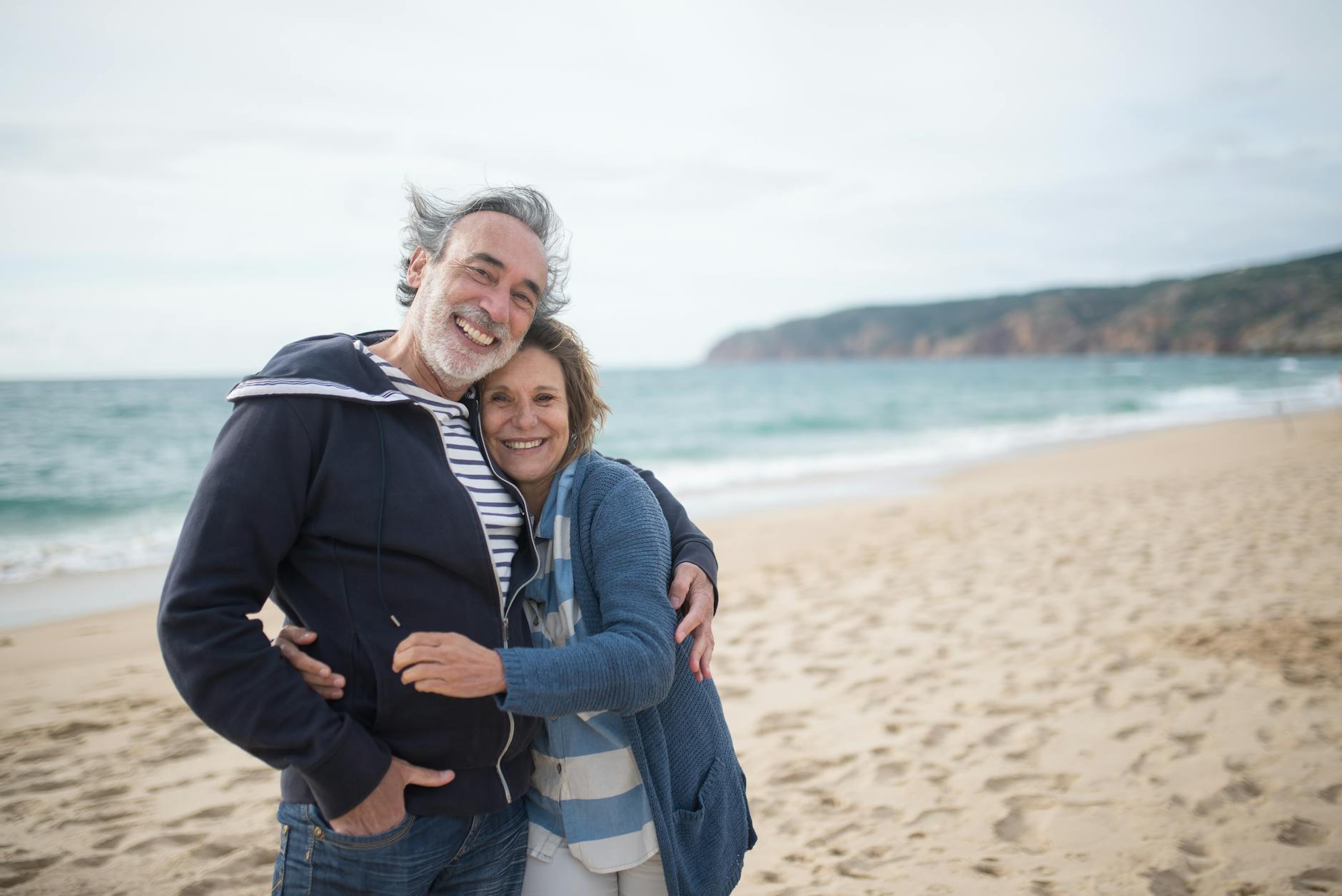 Happy senior couple embracing on a beach symbolizing travel and togetherness