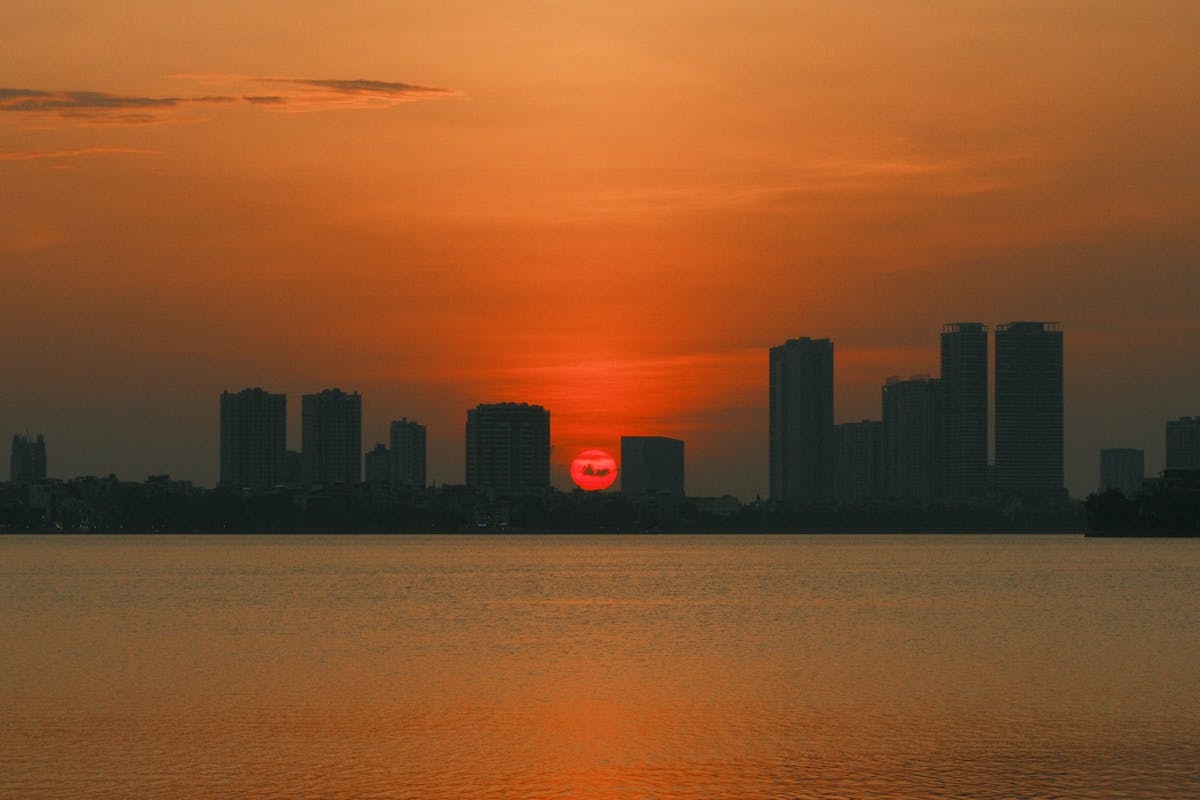 Stunning sunset over Hanoi skyline with vibrant orange colors reflected on water