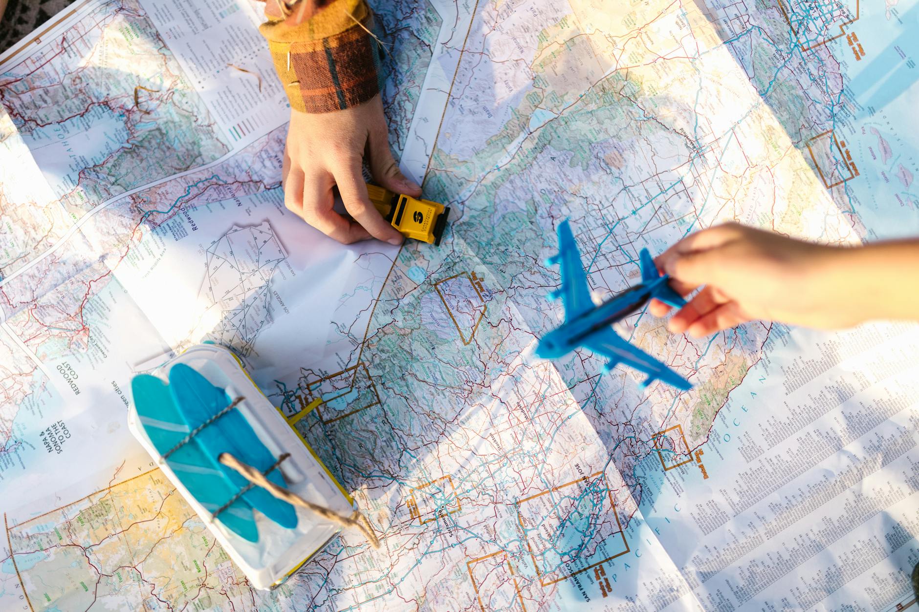Hands holding toy airplane and car over a map planning Hanoi trip
