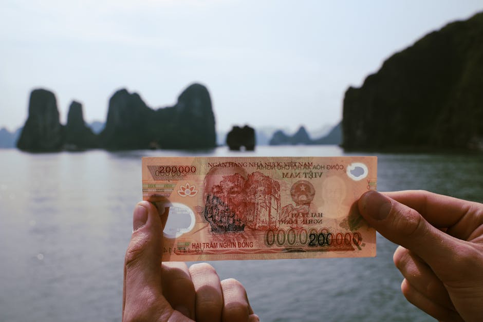 Hands holding Vietnamese Dong with Halong Bay